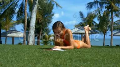 穿橙色泳装的女孩在草坪上阅读书籍
